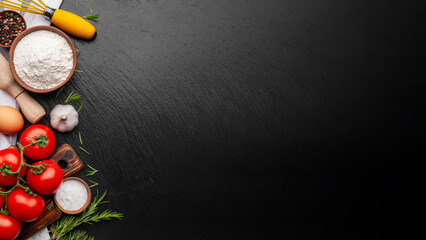 Cooking background of flour greens spices and eggs on slate dark board with copy-space
