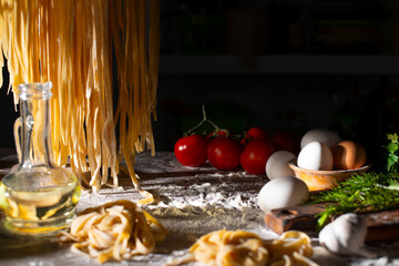 Homemade noodles hanging on wooden dryer rack over messy kitchen table background low angle front...