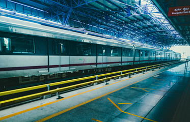 A modern train at a Bengaluru metro station in India, viewed from a low angle, emphasizing the...