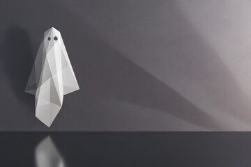 Minimalist Origami Ghost in Dramatic Lighting Against Gray Wall.