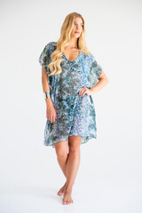 Fashionable blonde model in sheer beach pareo dress with leaf pattern, posing in studio for summer...