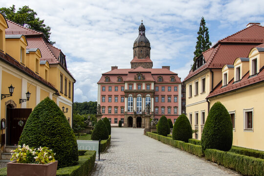 View of a historic pink castle with symmetrical garden path
