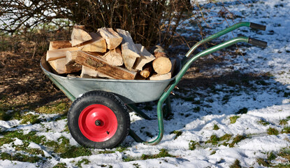 wheelbarrow in the snow full of firewood