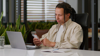 American multiracial businessman worker business man guy male work break pause holding mobile phone at desk smartphone texting message in web chat surfing corporate network reading news online using