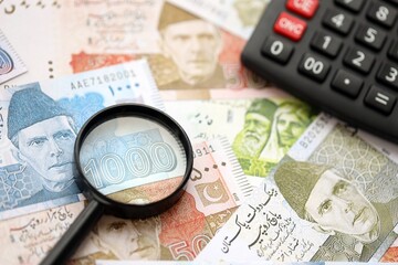 Pakistan rupees banknotes and calculator with magnifying glass. Pakistan money bills calc with loupe