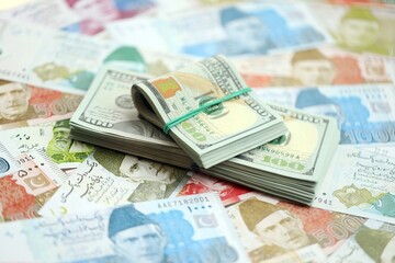 Bunch of US dollar bills lies on big amount of Pakistan rupees banknotes close up