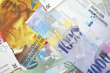 Swiss franc banknotes and medicine bottles. The current francs money bills and injection dose