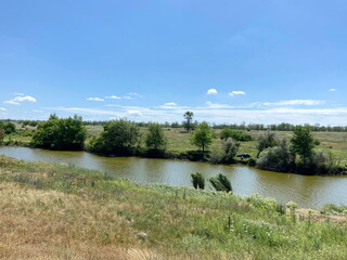 Panorama of the small Moskovka river flowing through the Zaporizhzhia steppe surrounded by field...