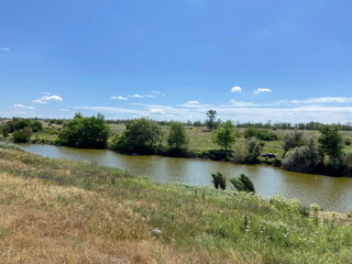Panorama of the small Moskovka river flowing through the Zaporizhzhia steppe surrounded by field...