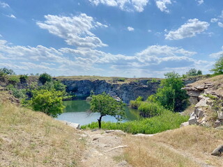 Descent down to the shore of a steppe lake created by nature in an abandoned granite quarry.