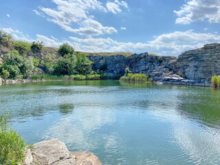 Panorama of impregnable stone cliffs surrounding the steppe lake, on which steppe vegetation breaks...