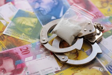 Swiss franc banknotes and cocaine pack with handcuffs. The current francs money bills and cuffs