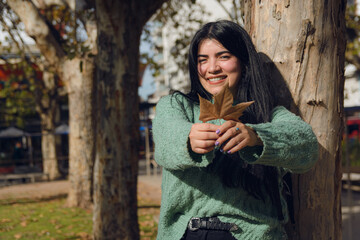 young woman in the park laughing with a dry autumn leaf
