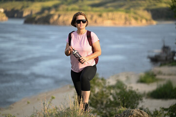 female tourist walking with backpack on beach and rocks