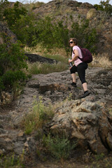 Naklejka premium female tourist walking with backpack on beach and rocks