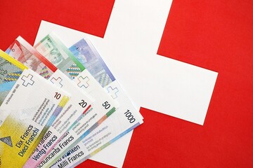 Swiss franc banknotes and flag. The current francs money bills lies on flag in big amount