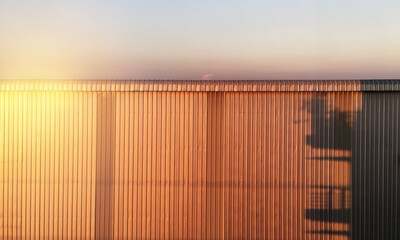 Building exterior material metal sheet wall of factory shiny with bright light and beautiful shade and shadow with twilight sky background.
