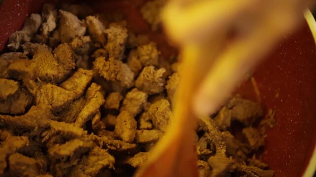 Carne sendo mexida dentro de panela com concha de madeira. 