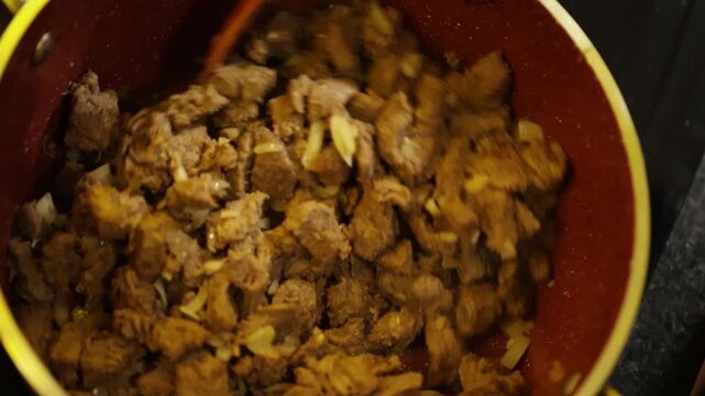 Carne sendo mexida dentro de panela com concha de madeira. 