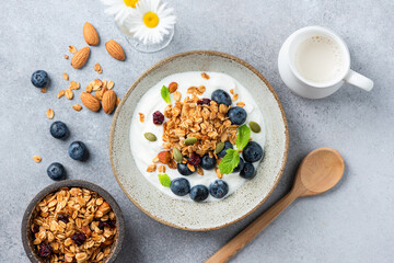 Greek yogurt bowl with crunchy granola and blueberries on grey concrete table background, top view,...