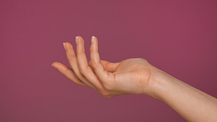 Female hand gesture with curved fingers on pink background