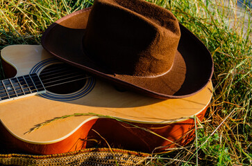Classical guitar on the grass by the lake and a cowboy hat