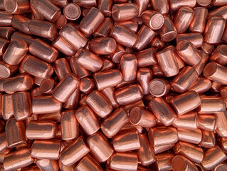 Close-up textured background of copper .44 Magnum caliber Full Metal Jacket (FMJ) bullets. Reloading components for revolver ammunition and manufacturing concept.