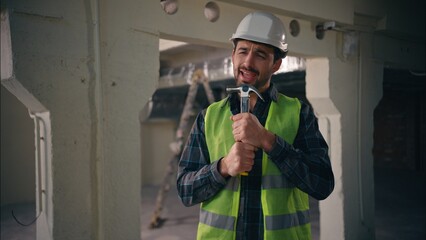 Cheerful active Caucasian man builder holding hammer working tool using as microphone singing song positive enjoy music male guy architect contractor engineer building construction repairman workman