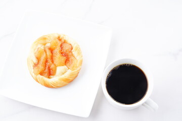 Delicious apple danish with a cup of fresh coffee on the white plate
