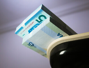 Bundle Stacks of 5 Ghanaian cedi notes cash money currency with white straps placed at the tip edge of desk. Below Low level angle view