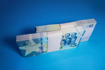 Double Bundle Stacks of 5 Ghanaian cedi notes cash money currency with white straps placed upright on its side isolated on blue background . Top view