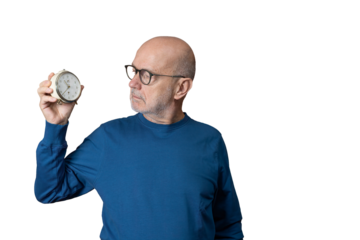 a man looks at an old alarm clock in his hand