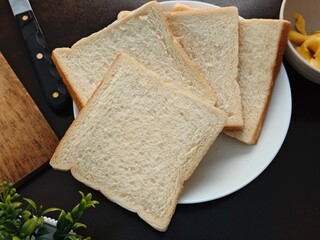 Sliced Bread on Plate with Knife and Cheese Spread Dark Background.