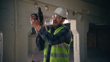 Angry Caucasian foreman male guy engineer man builder holding drill electric tool constructor...