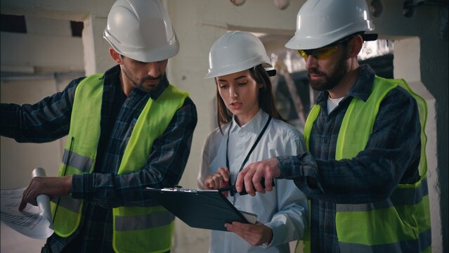 Caucasian builders woman men discussing building in construction contractors colleagues working negotiation cooperation blueprint site inspectors architects talk radio set build manufacturing industry - Powered by Adobe