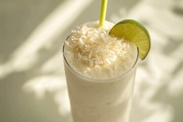 Refreshing coconut lime smoothie, topped with shredded coconut and a lime wedge.