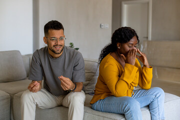 Couple fighting at home sitting on the sofa.