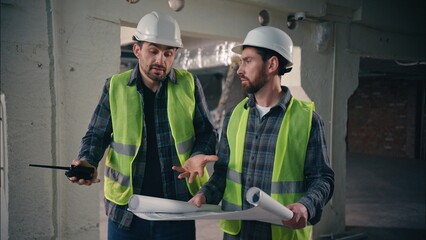 Two contractors civil engineers discuss arguing Caucasian men builders males conflict problem architects workers talking blueprint paper disagreement guys teamwork building project plan construction