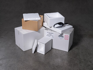 Collection of white shipping boxes with hazmat labels and black scoop containing dry ice pellets