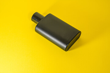 Black muffler lying on a bright yellow surface, showcasing its smooth, cylindrical shape and dark...