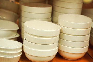 Stacks of pristine white bowls and lids neatly arranged on a shelf, showcasing kitchenware.