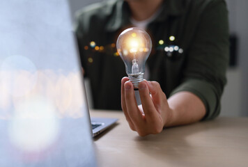 Hand holding a glowing light bulb symbolizes creativity, education, knowledge, online learning,...