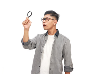 Young man using a magnifying glass with a curious expression on white background