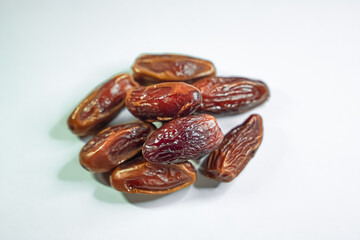 A small pile of dried dates rests on a plain white background.