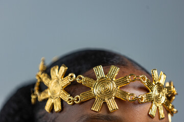 Close-up of African woman wearing golden headpiece on her forehead. Symbolic of royalty, beauty,...
