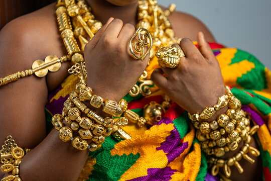 Rich Ghanaian royalty regalia. Traditional African culture and heritage, gold ring jewellery, necklace and bracelet ornaments worn on Kente cloth.