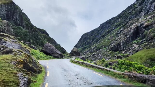 Car driving on the serpantine mountain road under the rain passing the Gap of Dunloe, County Kerry, Ireland. Slow motion, 4K