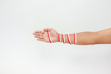 An isolated human hand with red and white ribbons, celebrating Indonesian independence day on a clear background