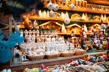 A crowded vendor table displaying small handcrafted figurines, ornaments, and holiday-themed characters at a Christmas market stall.