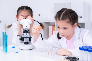 Learning and education for student in classroom, children focus on pipette handling and microscope...